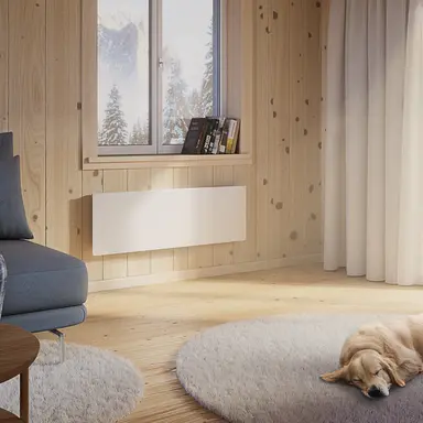 Elradiatorn Wallflex 600 Wifi på väggen i en stuga, vinterlandskap utanför och en hund på golvet
